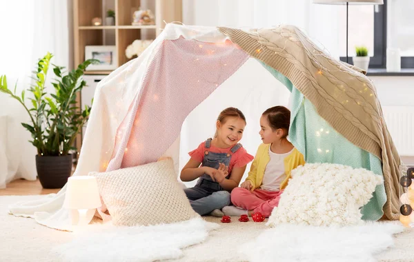Pieni tyttö leikkii teekutsuja lasten teltassa kotona — kuvapankkivalokuva