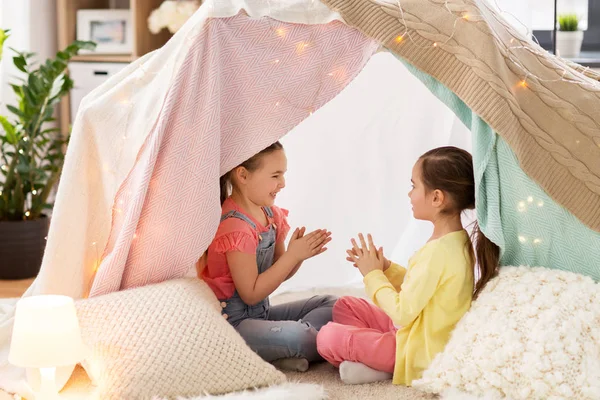 Girls playing clapping game in kids tent at home — Stock Photo, Image