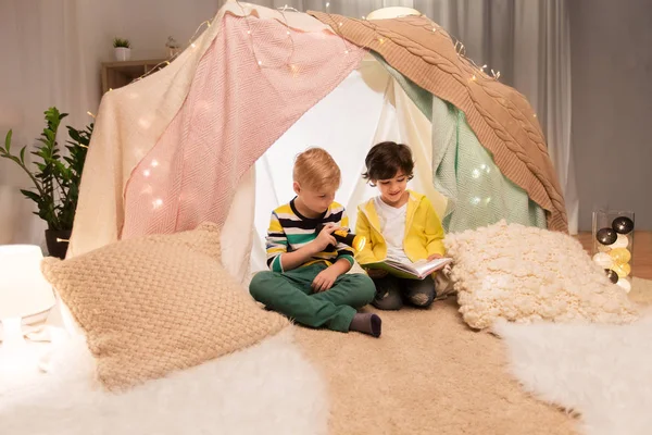 Ragazzi felici leggere libro in tenda per bambini a casa — Foto Stock