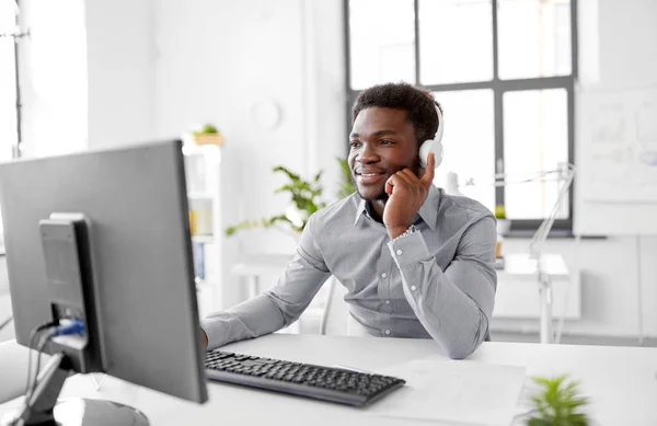 Hombre de negocios con auriculares y computadora en la oficina — Foto de Stock