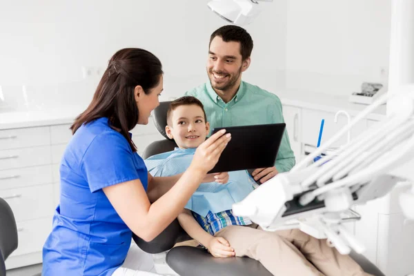 Dentista mostrando tablet pc para criança na clínica odontológica — Fotografia de Stock