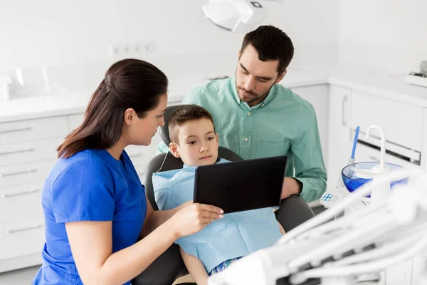 Dentista mostrando tablet pc para criança na clínica odontológica — Fotografia de Stock