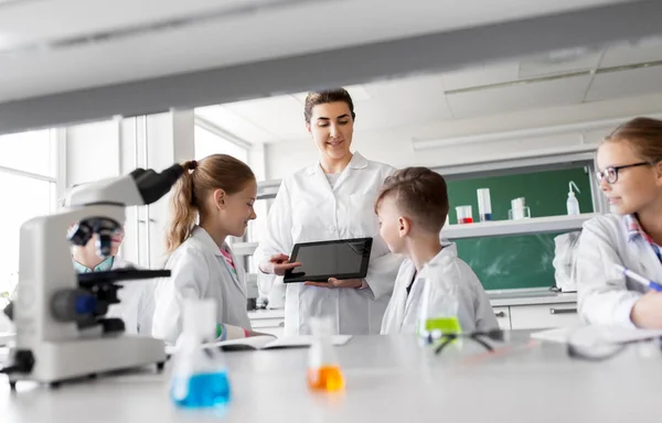 Insegnante con tablet pc e bambini a lezione di chimica — Foto Stock
