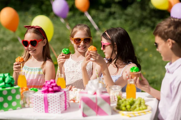 Діти їдять кекси на день народження влітку — стокове фото