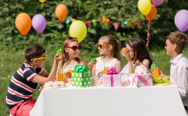 Niños comiendo cupcakes en fiesta de cumpleaños en verano —  Fotos de Stock