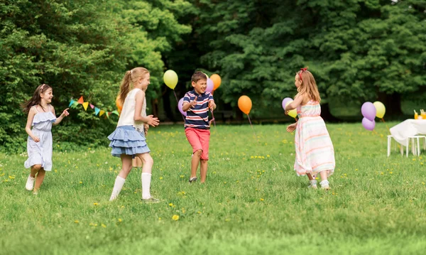 Счастливые дети играют в игру тегов на дне рождения — стоковое фото