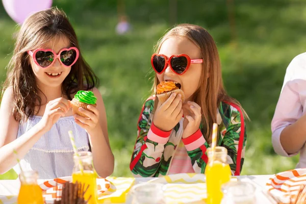 Bambini che mangiano cupcake alla festa di compleanno in estate — Foto Stock