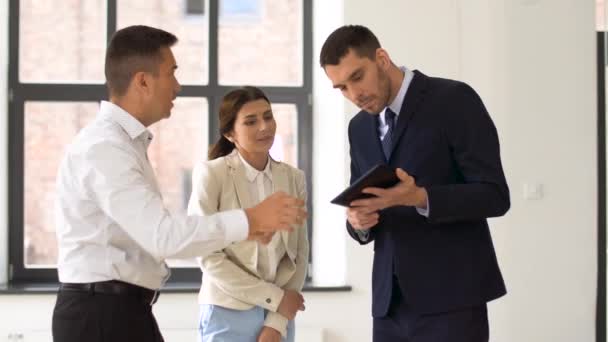 Corretor de imóveis mostrando tablet pc para clientes no escritório — Vídeo de Stock