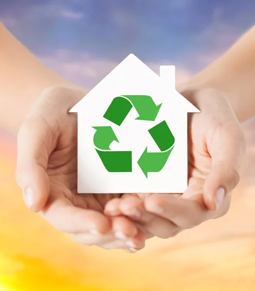 Руки тримають будинок з зеленим знаком переробки — стокове фото