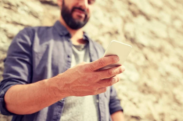 Close up of man with smartphone at stone wall — Stock Photo, Image