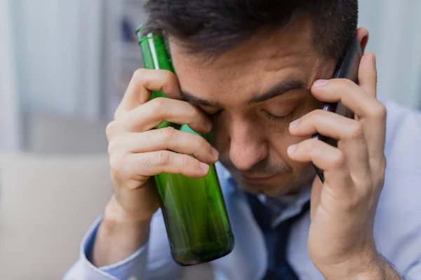 Homem com garrafa de álcool chamando no smartphone — Fotografia de Stock