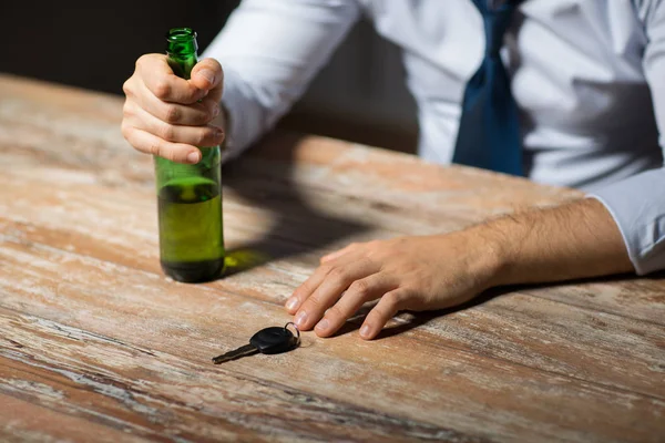 Primer plano de las manos con alcohol y la llave del coche — Foto de Stock