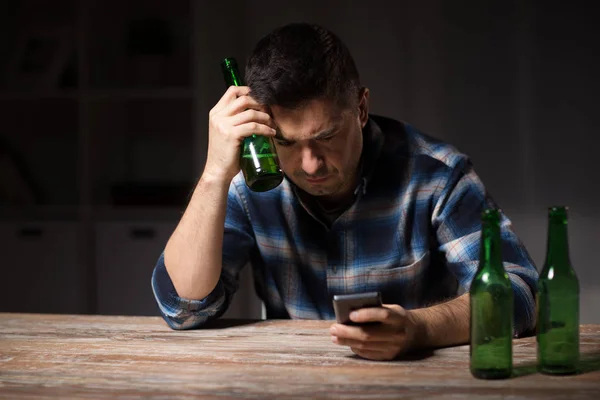 Homme avec smartphone et bouteille de bière la nuit — Photo