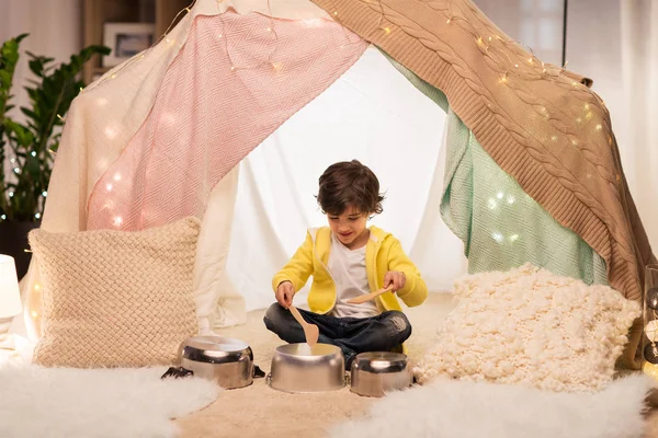 Niño con ollas tocando música en tienda de campaña para niños en casa —  Fotos de Stock