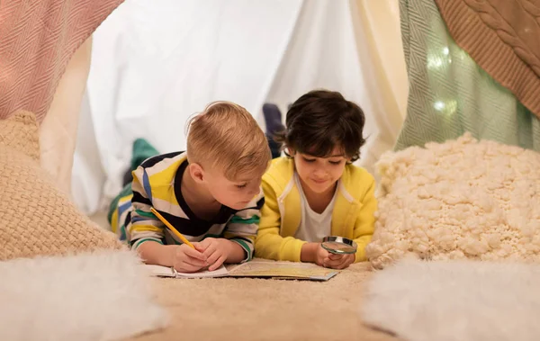 Niños con lupa y mapa en tienda de campaña para niños en casa —  Fotos de Stock