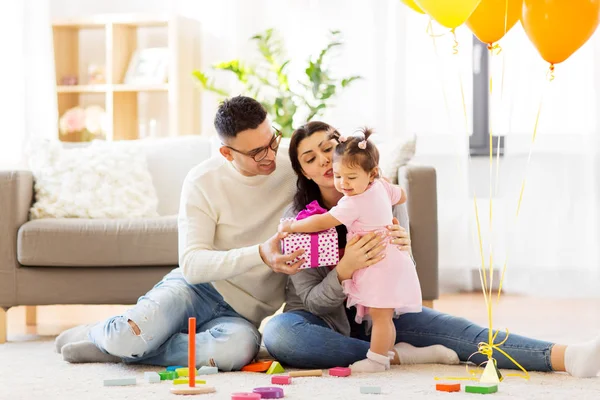 Baby girl with birthday gift and parents at home — Stock Photo, Image