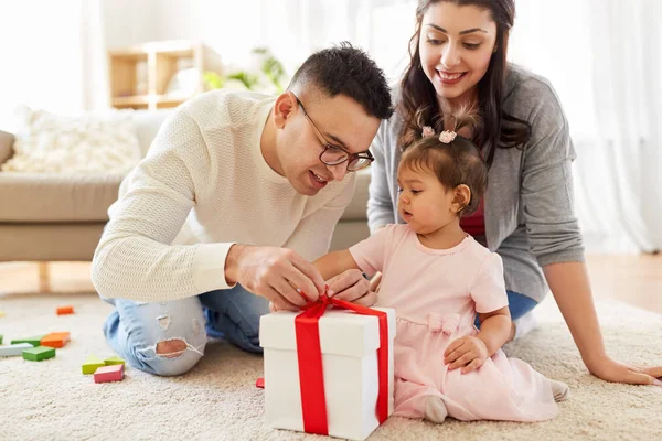 Baby girl with birthday gift and parents at home — Stock Photo, Image