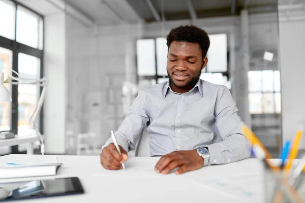 Empresário afro-americano com papéis no escritório — Fotografia de Stock