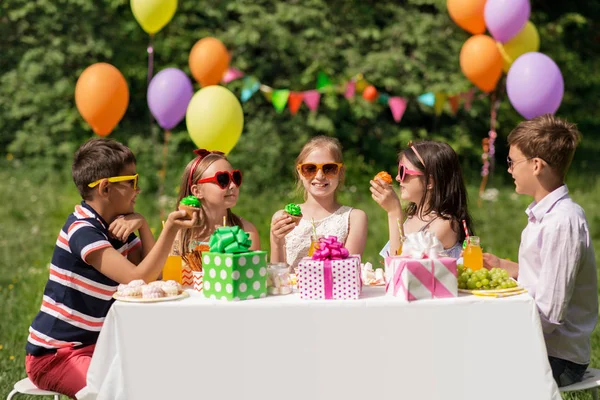 Τα παιδιά τρώνε cupcakes σε πάρτι γενεθλίων στο καλοκαίρι — Φωτογραφία Αρχείου