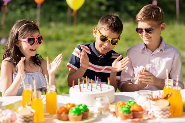 Gelukkige jonge geitjes met cake op verjaardag partij op de zomer — Stockfoto