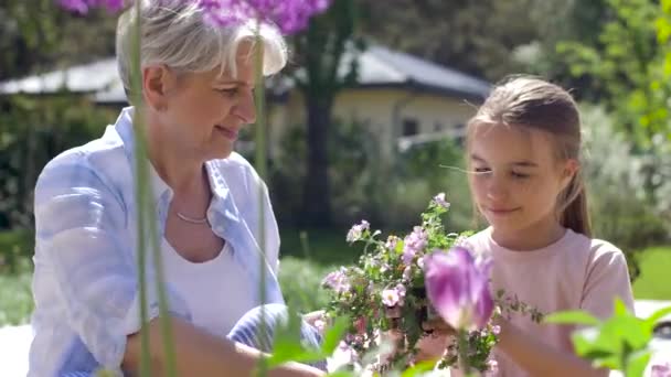 Grootmoeder en meisje planten van bloemen in de tuin — Stockvideo