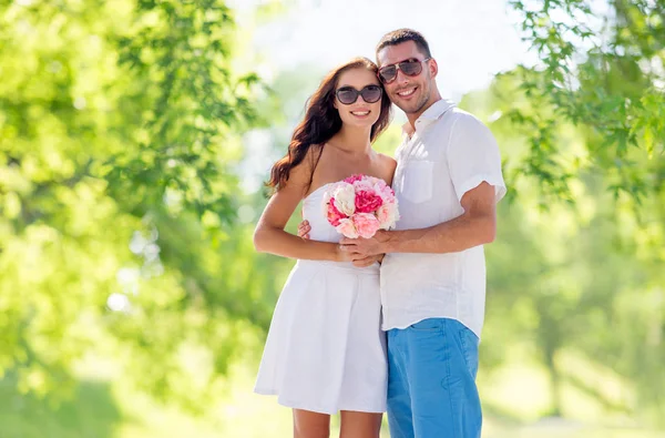 Happy couple with bunch of flowers hugging — Stock Photo, Image