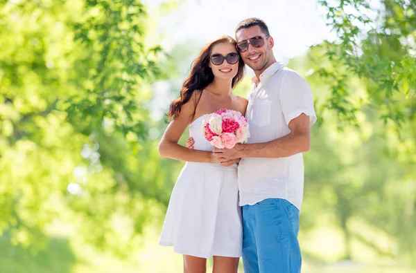 Feliz pareja con ramo de flores abrazos — Foto de Stock