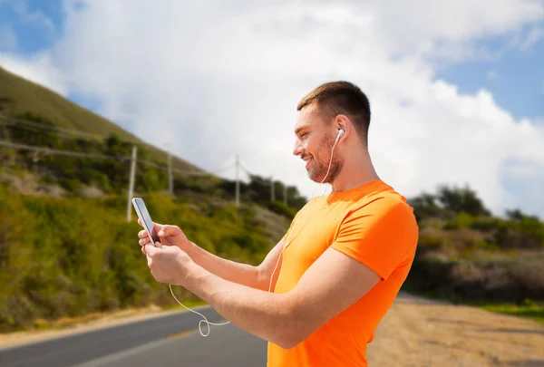 Man with smartphone and earphones over big sur — Stock Photo, Image