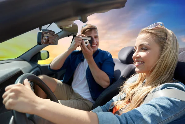 Man photographing woman driving car by film camera — Stock Photo, Image