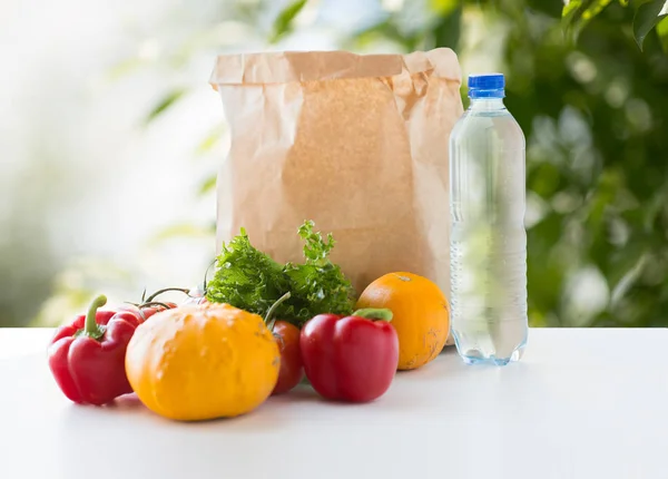 Saco de papel com comida vegetal e água na mesa — Fotografia de Stock