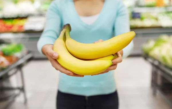 Vrouw met bananen in supermarkt — Stockfoto