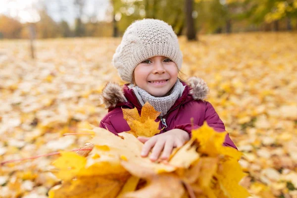 Fată fericită cu frunze de arțar căzute în parcul de toamnă — Fotografie, imagine de stoc