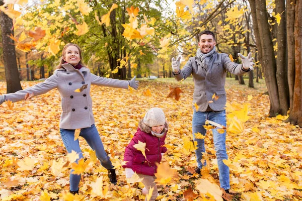 Glückliche Familie spielt im Park mit Herbstlaub — Stockfoto