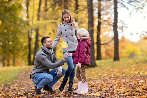 Счастливая семья с кленовым листом в осеннем парке — стоковое фото