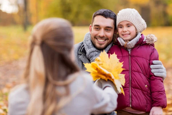 Glückliche Familie mit Ahornblättern im Herbstpark — Stockfoto