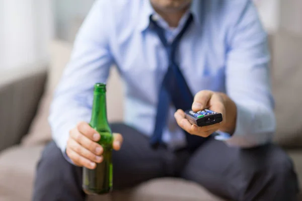 Close up of man with tv remote drinking beer — Stock Photo, Image