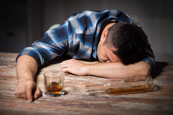 Homem bêbado com copo de álcool na mesa à noite — Fotografia de Stock