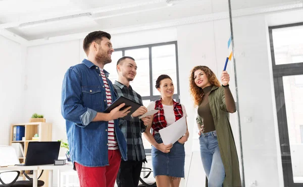 Equipo creativo mirando el tablero de cristal en la oficina — Foto de Stock