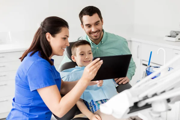 Dentista mostrando tableta PC a niño en la clínica dental —  Fotos de Stock