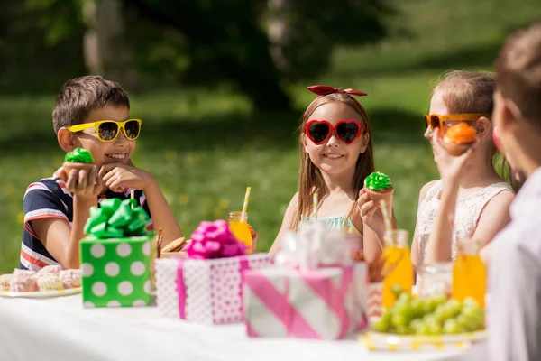 Niños comiendo cupcakes en fiesta de cumpleaños en verano —  Fotos de Stock