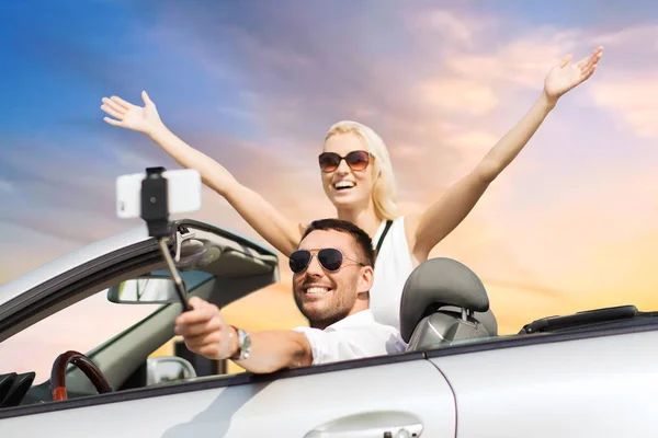 Casal em carro tomando selfie por smartphone sobre o céu — Fotografia de Stock