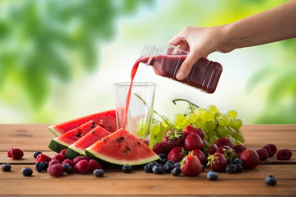 Menuangkan jus buah dari botol ke gelas — Stok Foto
