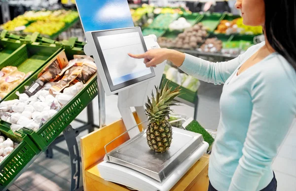 Mulher pesando abacaxi em escala no supermercado — Fotografia de Stock