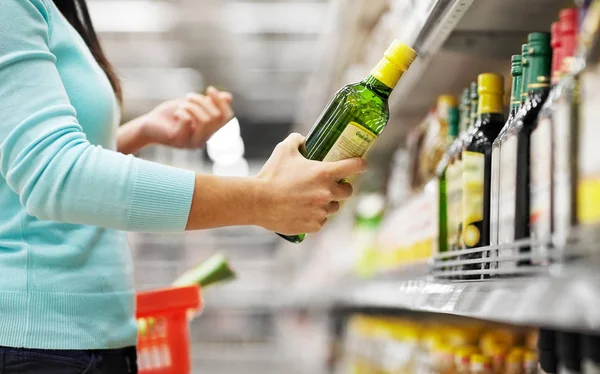 Frau kauft Olivenöl im Supermarkt oder Lebensmittelgeschäft — Stockfoto