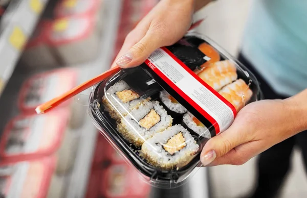 Manos con paquete de sushi en el supermercado o supermercado —  Fotos de Stock