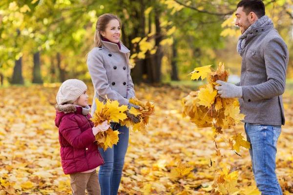 Щаслива сім'я грає з осіннім листям у парку — стокове фото