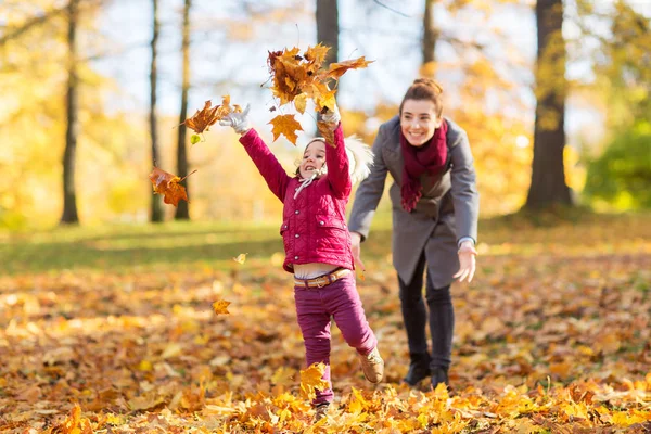 Lycklig familj spelar med hösten lämnar på park — Stockfoto