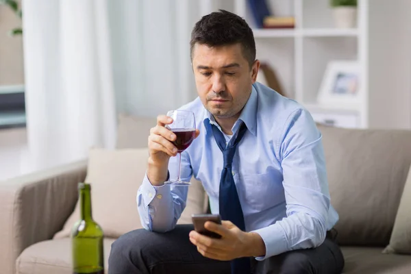 Homem bêbado com álcool e smartphone em casa — Fotografia de Stock