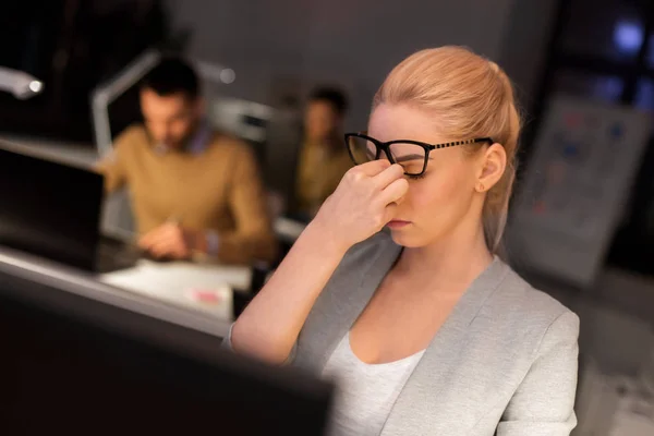 Empresária esfregando olhos cansados no escritório da noite — Fotografia de Stock