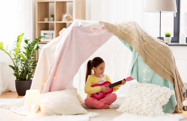 Dívka hrající hračka kytaru ve stanu děti doma — Stock fotografie